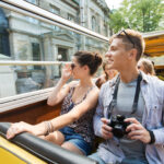 smiling couple with camera traveling by tour bus