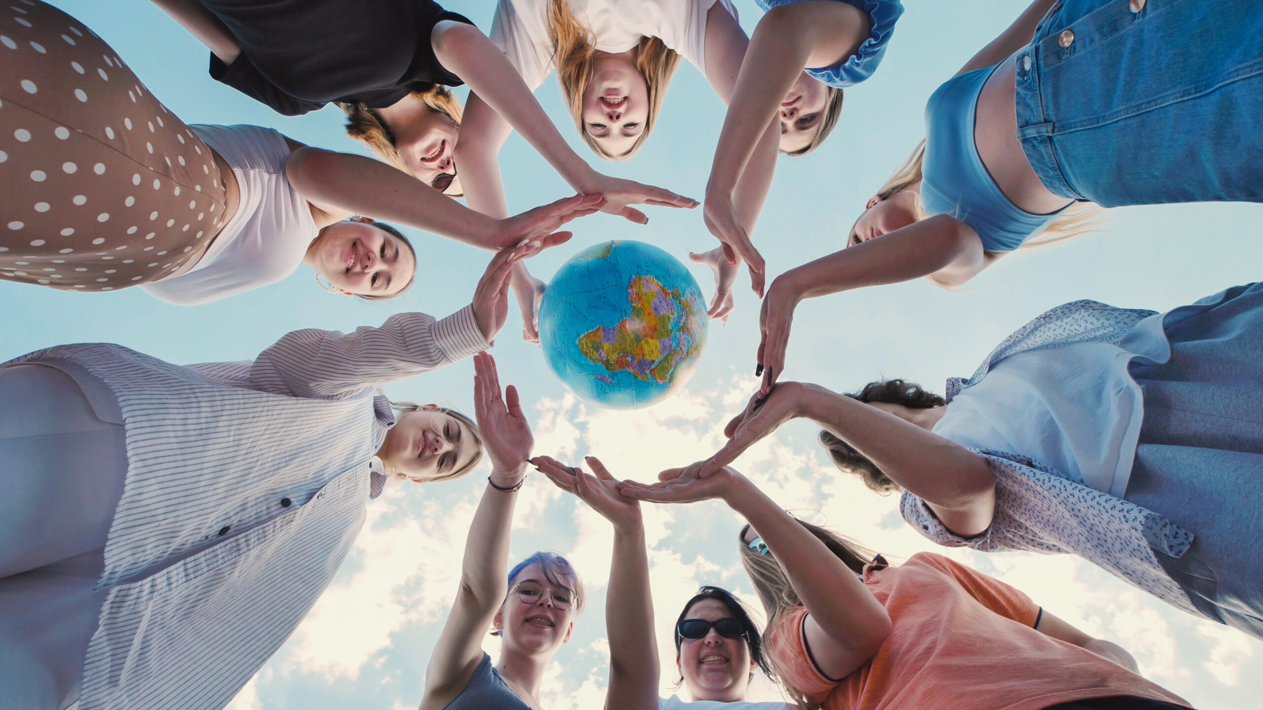 School friends joining hands in a circle around a globe, representing unity, environmental consciousness, and global citizenship
